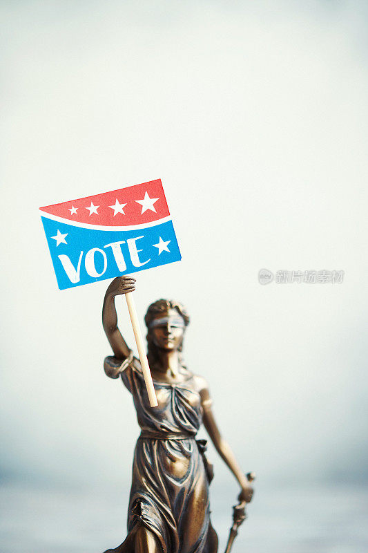 Lady Justice with reminder to vote sign